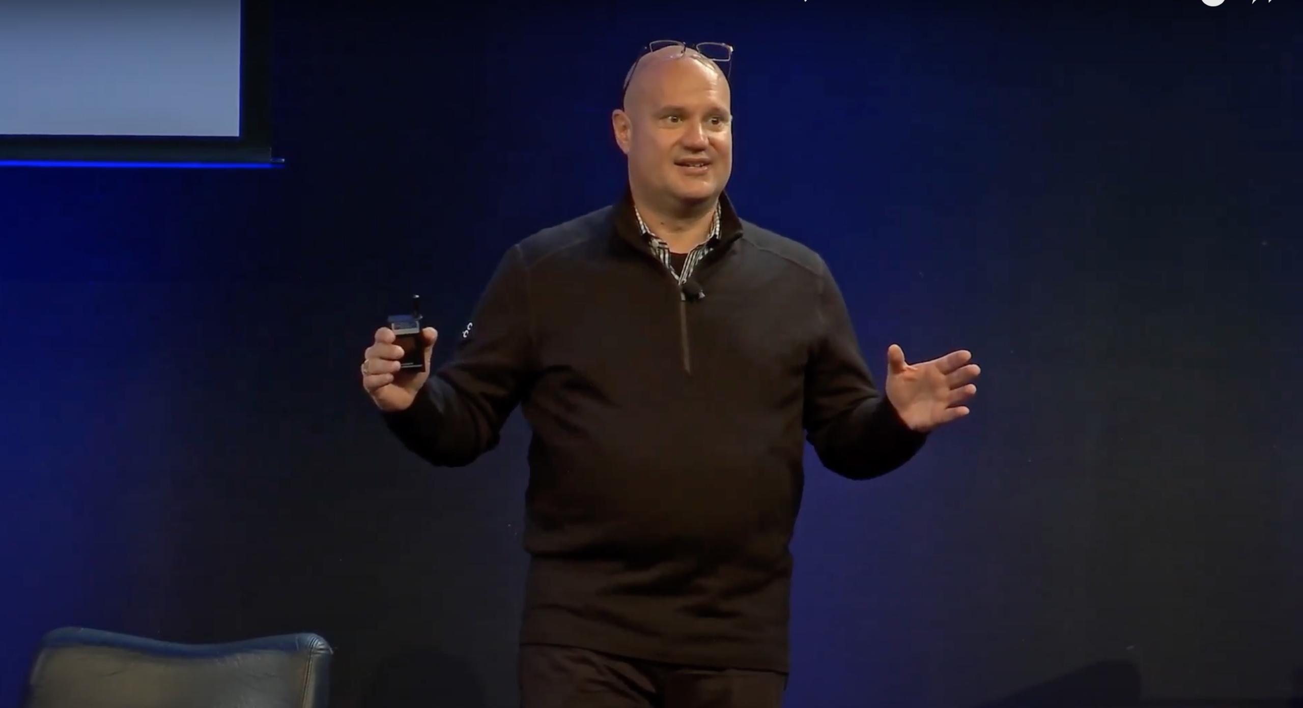A speaker addressing an audience on a darkened stage
