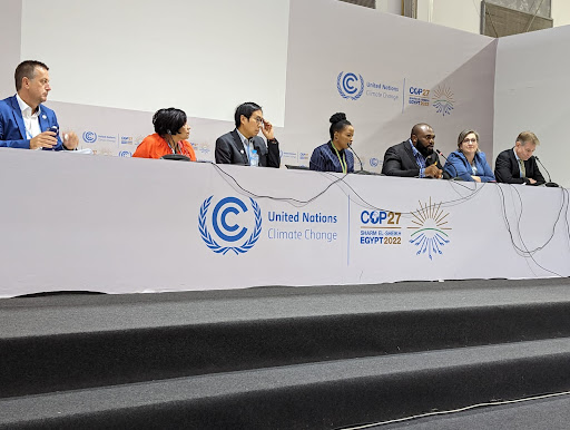 Panelists seated at a long table during a COP27 session
