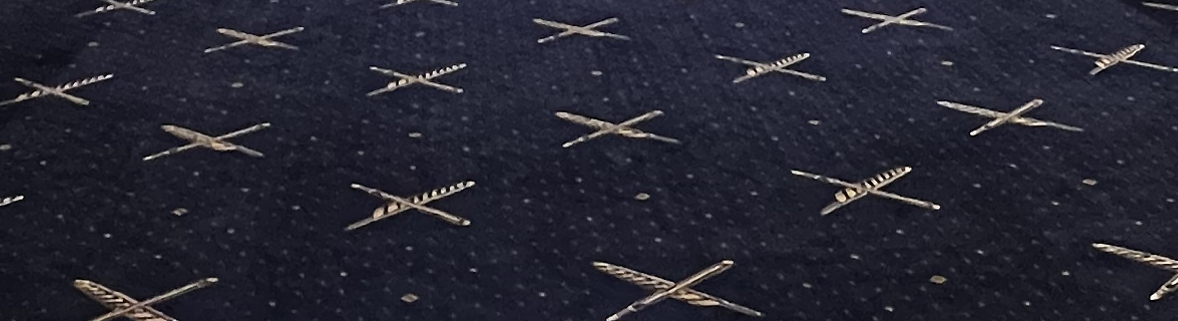 Close-up of dark navy fabric patterned with small gold crossed motifs
