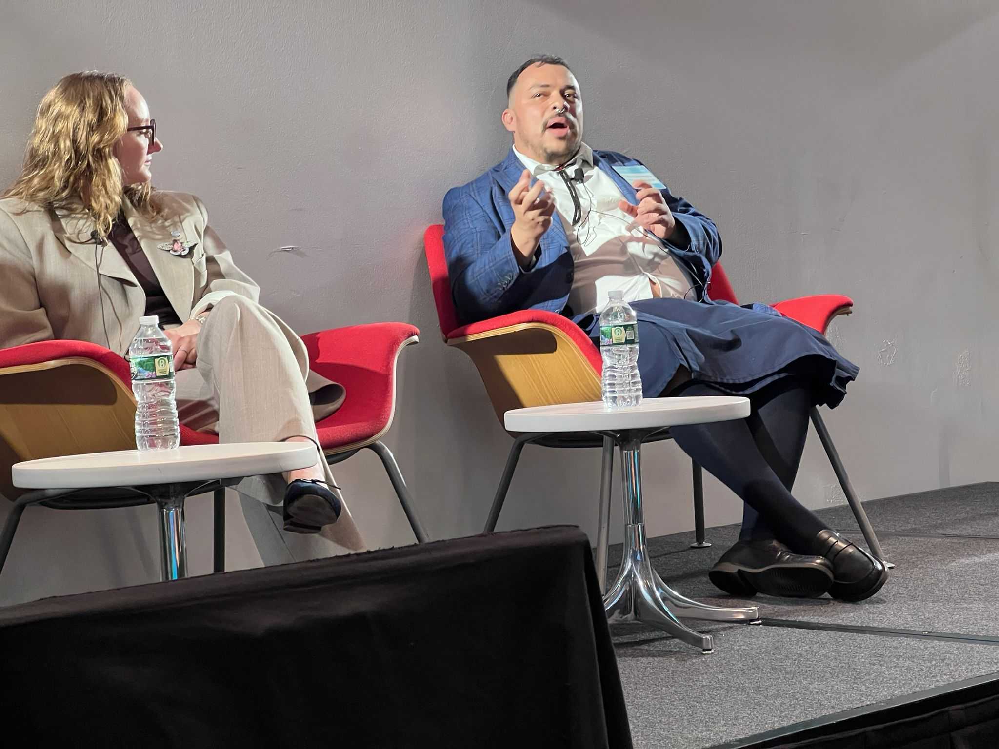 Guido Núñez-Mujica speaking with a microphone beside a fellow panelist on stage