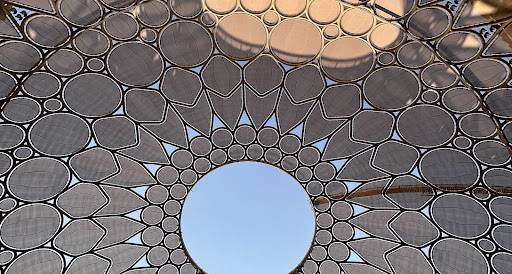 Looking up at the latticed Al Wasl dome canopy at the COP28 venue in Dubai, with a circle of sky at its centre